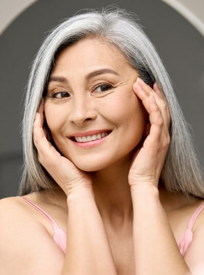 Anti-aging procedures - older woman looking at herself in the mirror