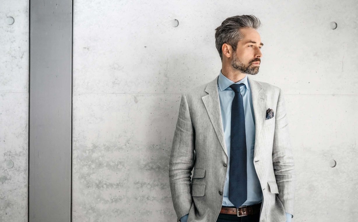 Man in a gray suit against a gray wall