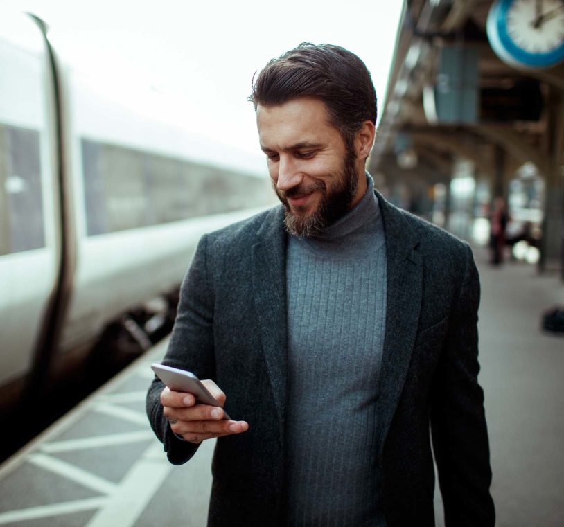 Man checking his phone at a train station platform