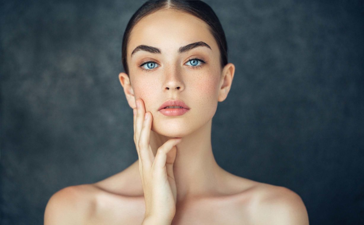 Blue eyed woman with freckles showing her perfect face