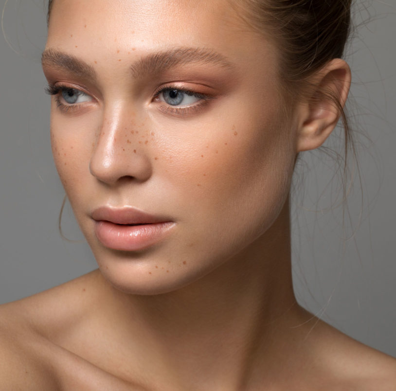 Blue eyed woman with freckles showing her perfect face