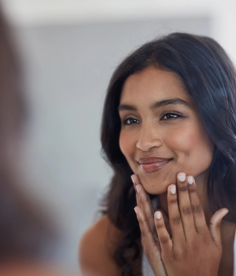 A woman looking into a mirror and touching her face